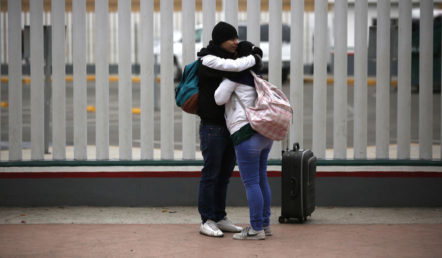Migrants embraces after receiving one of the fifty turns for an interview to request U.S. asylum, alongside the El Chaparral pedestrian border crossing in Tijuana, Mexico, Friday, Dec. 21, 2018. (AP Photo/Moises Castillo)