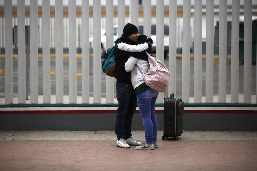 Migrants embraces after receiving one of the fifty turns for an interview to request U.S. asylum, alongside the El Chaparral pedestrian border crossing in Tijuana, Mexico, Friday, Dec. 21, 2018. (AP Photo/Moises Castillo)