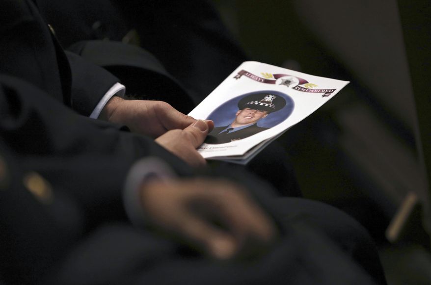 An attendee holds a program as police officers attend the funeral for Chicago police Officer Conrad Gary, Friday, Dec. 21, 2018 at St. Rita of Cascia Shrine Chapel in Chicago. Gary was one of two Chicago officers who were struck and killed by a commuter train as they were investigating a report of gunfire in the area. (Abel Uribe/Chicago Tribune via AP, Pool)