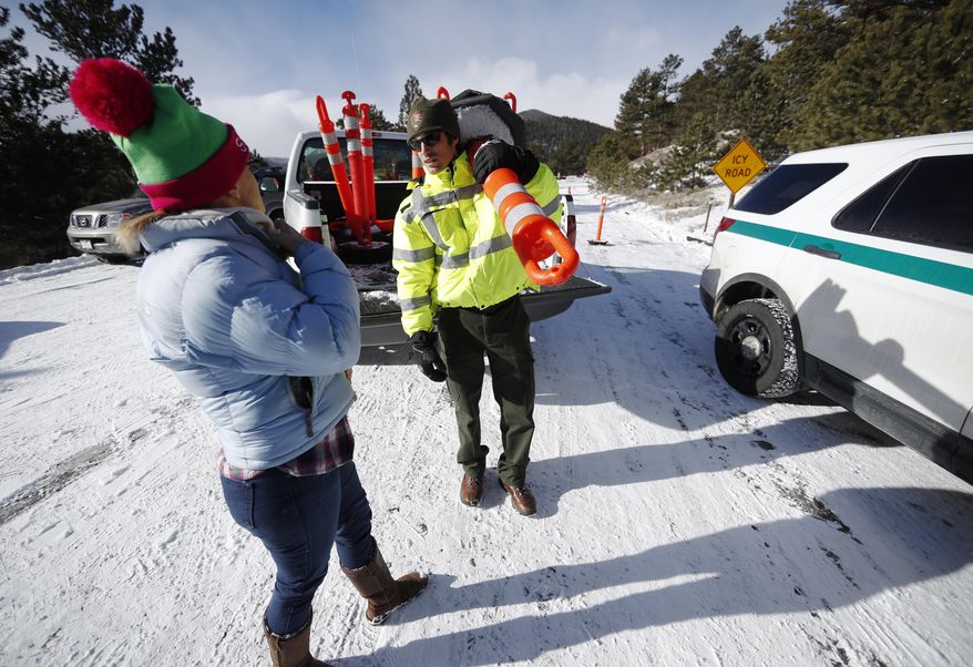 Park ranger Kevin Sturmer, right, tells Sarah Schlesinger of Boulder, Colo., that Trail Ridge Road is blocked to vehicles after a light overnight snow in Rocky Mountain National Park Saturday, Dec. 22, 2018, in Estes Park, Colo. The road was unplowed because of a partial federal shutdown that has been put in motion because of gridlock in Congress over funding for President Donald Trump's Mexican border wall. (AP Photo/David Zalubowski)