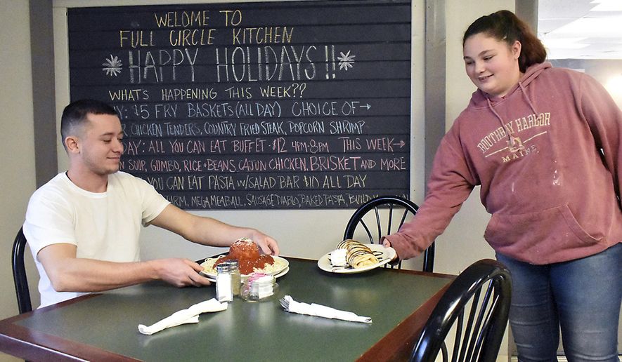 FILE - In this Dec. 12, 2018 file photo, Reagan Swartz, right, serves Michael Carder a crepe and plate of the restaurant spaghetti and giant meatball at Full Circle Kitchen in Rivesville, West Va. The restaurant will serve a Christmas buffet from 11:00 a.m. to 3 p.m. on Christmas day. (Tammy Shriver/Times-West Virginian via AP, File)