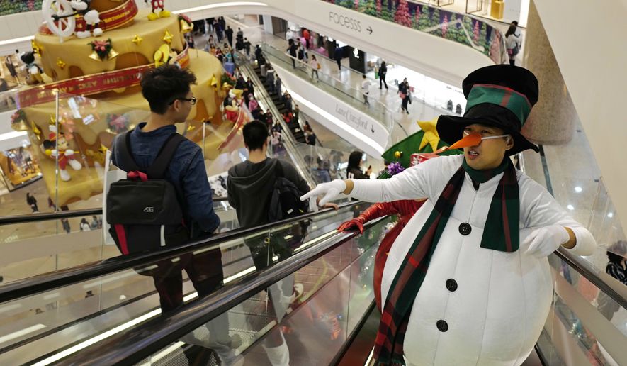 Promoters dressed as Christmas characters get on an escalator at a shopping mall as the territory prepares to celebrate the Christmas holidays, in Hong Kong Monday, Dec. 24, 2018. (AP Photo/Vincent Yu)