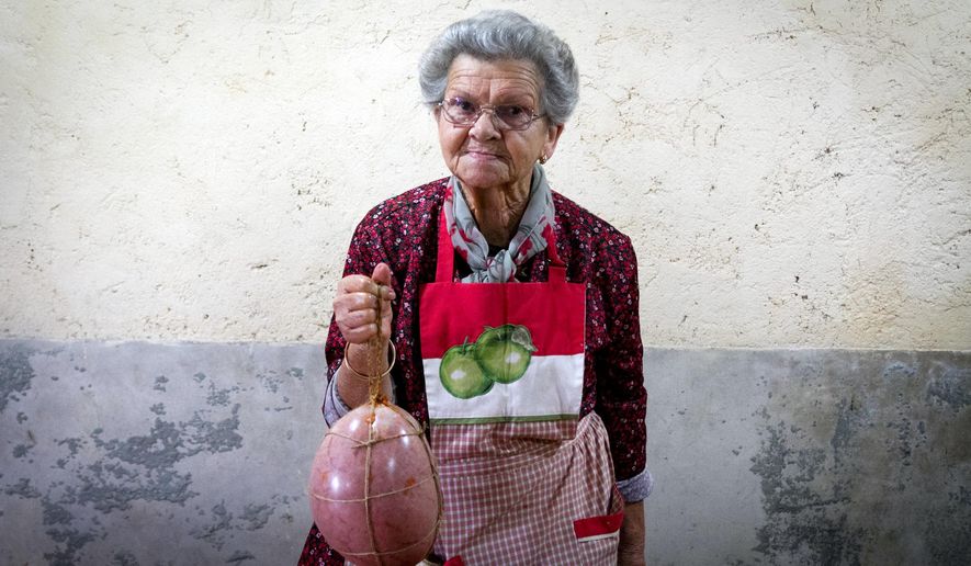 In this photo taken on Nov. 24, 2018, Francisca holds a sobrasada, a raw cured sausage, made of pork bladder during the annual pig slaughter near Petra, some 60 kilometres from Palma, the capital of Mallorca, Spain. Beneath wintry gray skies on the Mediterranean island of Mallorca, families, friends and neighbors gather for a centuries-old tradition that is not for the faint-hearted: the open-air slaughter of a pig, a custom which due to industrialization has been dying out. (AP Photo/Francisco Ubilla)