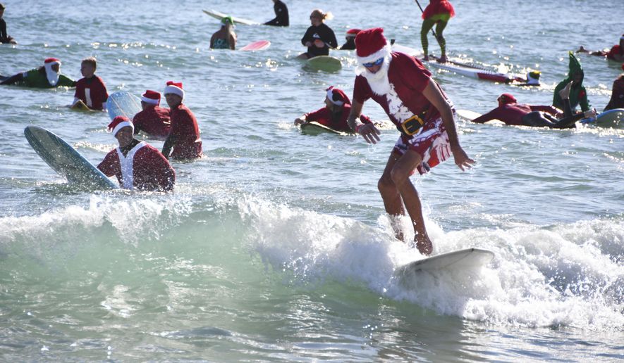 On Christmas Eve in 2009 George Trosset went surfing behind his house in Cocoa Beach in a Santa suit with his son and daughter-in-law. A photo made the local paper and next year some friends joined him in Santa suits of their own. Every year the event got bigger. This year thousands showed up in downtown Cocoa Beach for the annual Christmas Eve Surfing Santas event with hundreds of surfing Santas taking to the waves. The event now raises money for the Florida Surf Museum and Grind for Life. The weather was perfect Florida weather Monday morning with temperatures in the high 60's, unfortunately there were very small waves for the event. (Malcolm Denemark/Florida Today via AP)