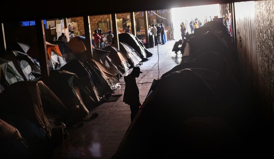 Honduran migrants stand inside an empty warehouse that opened its doors to migrants in downtown Tijuana, Mexico, Monday, Dec. 24, 2018. Discouraged by the long wait to apply for asylum through official ports of entry, many Central American migrants from recent caravans are choosing to cross the U.S. border wall and hand themselves in to border patrol agents. (AP Photo/Daniel Ochoa de Olza)