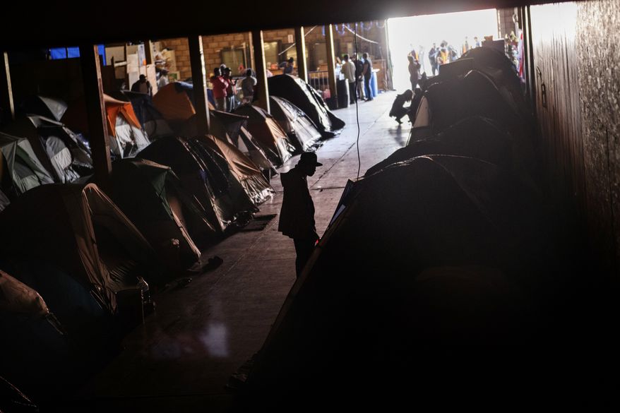 Honduran migrants stand inside an empty warehouse that opened its doors to migrants in downtown Tijuana, Mexico, Monday, Dec. 24, 2018. Discouraged by the long wait to apply for asylum through official ports of entry, many Central American migrants from recent caravans are choosing to cross the U.S. border wall and hand themselves in to border patrol agents. (AP Photo/Daniel Ochoa de Olza)