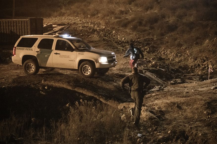 A border patrol officer fails to arrest a migrant running after jumping the United States border fence to San Diego, from Tijuana, Mexico, Tuesday, Dec. 25, 2018. Discouraged by the long wait to apply for asylum through official ports of entry, many Central American migrants from recent caravans are choosing to cross the U.S. border wall and hand themselves into border patrol agents. (AP Photo/Daniel Ochoa de Olza)