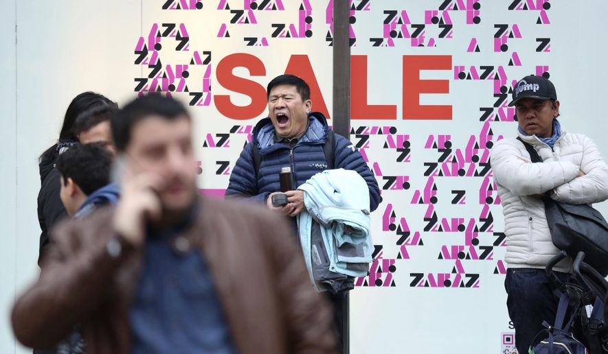 A shopper yawning while waiting outside a shop, during the Boxing Day sales, on Oxford Street, in London, Wednesday, Dec. 26, 2018. (Isabel Infantes/PA via AP)