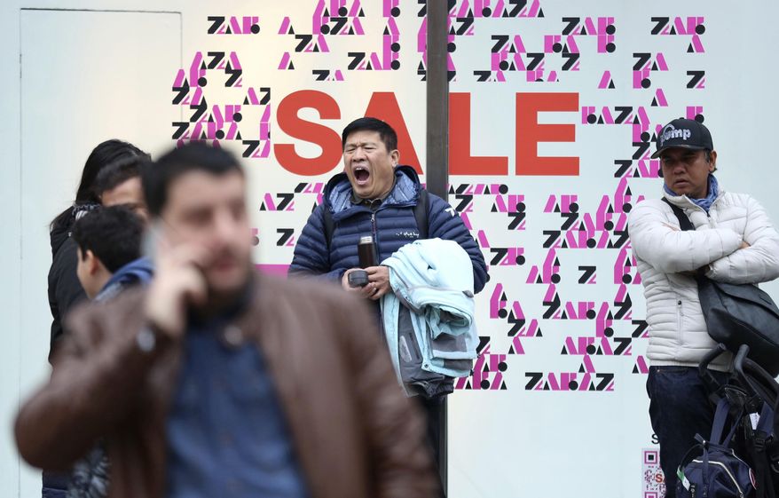 A shopper yawning while waiting outside a shop, during the Boxing Day sales, on Oxford Street, in London, Wednesday, Dec. 26, 2018. (Isabel Infantes/PA via AP)