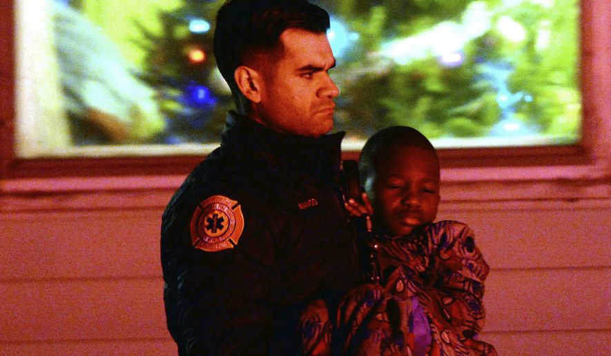 In this Tuesday, Dec. 25, 2018, photo, an officer carries an injured boy near the scene of a fatal house fire in Avon, Mass. (Marc Vasconcellos/The Enterprise via AP)