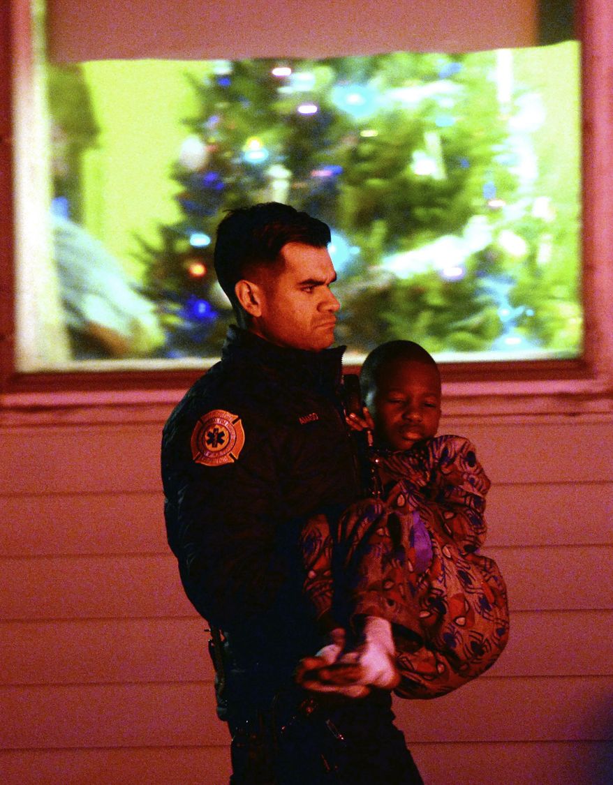In this Tuesday, Dec. 25, 2018, photo, an officer carries an injured boy near the scene of a fatal house fire in Avon, Mass. (Marc Vasconcellos/The Enterprise via AP)