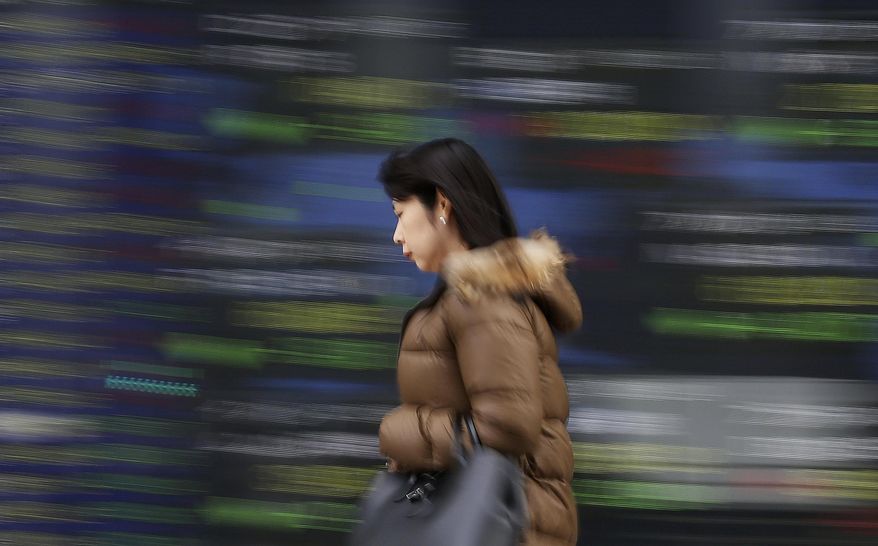 A woman walks by an electronic stock board of a securities firm in Tokyo, Wednesday, Dec. 26, 2018. Asian markets were mostly lower on Wednesday after President Donald Trump said that there was "nothing new" in efforts to end the partial government shutdown over a U.S.-Mexico border wall. (AP Photo/Koji Sasahara)