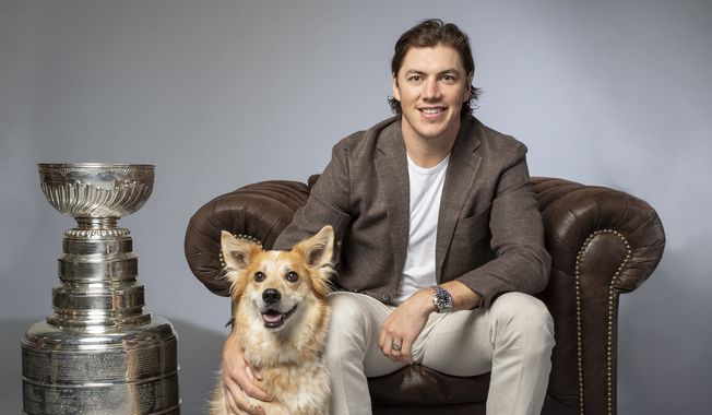 Washington Capitals forward T.J. Oshie poses with a dog and the Stanley Cup during the team&#x27;s 2019 Caps Canine Calendar photo shoot. (Photo by Virgil Ocampo Photography / courtesy of Washington Capitals)