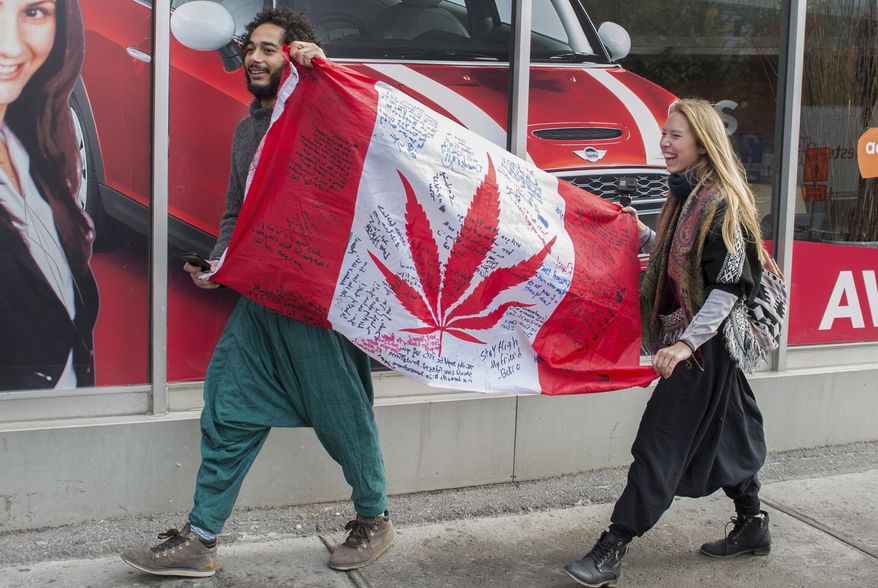 In this Oct. 17, 2018, file photo, people hold up a Canadian flag with a marijuana logo on it outside a government cannabis store in Montreal. California became America’s largest legal marketplace in 2018, while Canada became the second and largest country with nationwide legal recreational marijuana. (Graham Hughes/The Canadian Press via AP) **FILE**