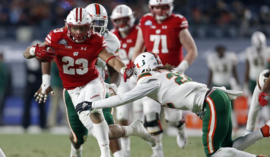 Wisconsin running back Jonathan Taylor (23) breaks a tackle attempt by Miami defensive back Sheldrick Redwine (22) during the first half of the Pinstripe Bowl NCAA college football game Thursday, Dec. 27, 2018, in New York. (AP Photo/Adam Hunger)