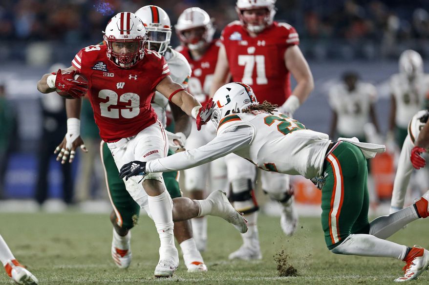 Wisconsin running back Jonathan Taylor (23) breaks a tackle attempt by Miami defensive back Sheldrick Redwine (22) during the first half of the Pinstripe Bowl NCAA college football game Thursday, Dec. 27, 2018, in New York. (AP Photo/Adam Hunger)