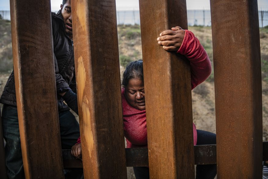 A migrant climbs the border fence before jumping into the U.S. to San Diego, Calif., from Tijuana, Mexico, Thursday, Dec. 27, 2018. Discouraged by the long wait to apply for asylum through official ports of entry, many Central American migrants from recent caravans are choosing to cross the U.S. border wall and hand themselves into border patrol agents. (AP Photo/Daniel Ochoa de Olza)