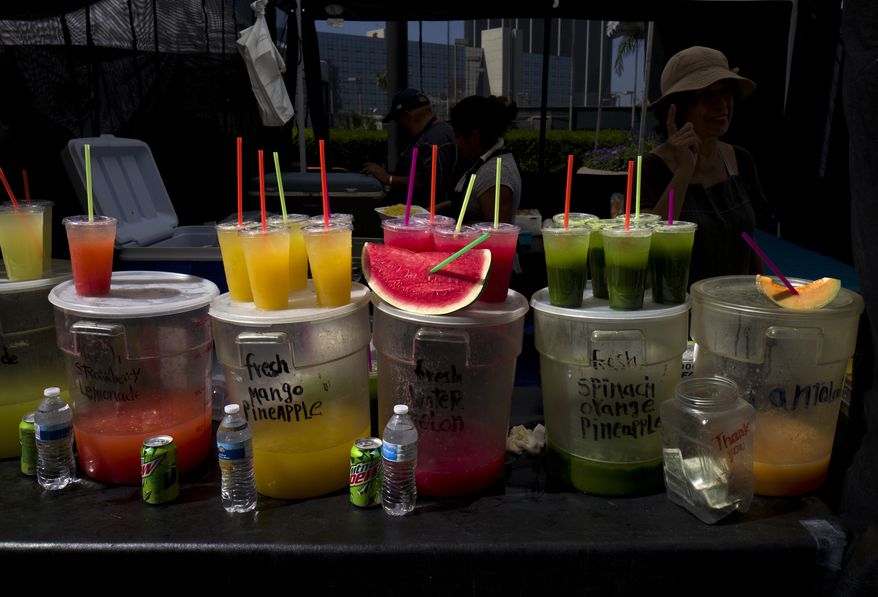 FILE - In this Sept. 21, 2018, file photo, a vendor sells fresh juices and fruit at a Farmers Market in downtown Los Angeles. A law signed Sept. 20 by Gov. Jerry Brown makes California the first state to bar full-service restaurants from automatically giving out single-use plastic straws. Dine-in restaurants may only provide drinking straws at customers' request. (AP Photo/Richard Vogel, File) **FILE**