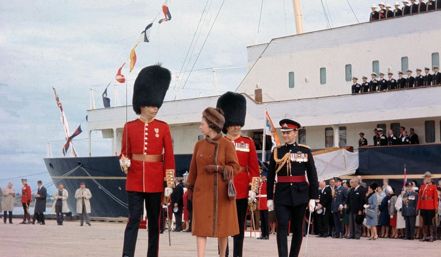 FILE - In this file photo dated Oct. 6, 1964, Britain's Queen Elizabeth II is escorted by Captain G. L. Simpson, as she leaves the Royal Yacht Britannia to inspect the 2nd Battalion of the Canadian Guard, on her arrival at Charlottetown, Canada. A newly discovered note dated 1995 in the U.K.’s National Archives Saturday Dec. 29, 2018, shows that Queen Elizabeth II let government officials know she would welcome a replacement for the Royal Yacht Britannia once it was decommissioned. The Royal Yacht Britannia was in service from 1954 to 1997. (AP Photo/FILE)