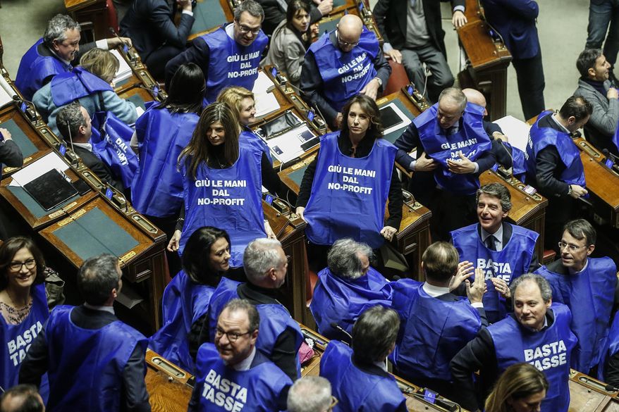 Forza Italia party's lawmakers protest wearing blue vest reading "stop taxes" and "hands off non-profit", referring to increasing taxes on non-profit sector workers, before the vote of confidence on the budget law at the Italian lower chamber in Rome, Saturday, Dec. 29, 2018 . (Fabio Frustaci/ANSA via AP)