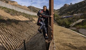 A Honduran migrant grabs his son as they climb the U.S. border fence before jumping into the U.S. to San Diego, Calif., from Tijuana, Mexico, Saturday, Dec. 22, 2018. Discouraged by the long wait to apply for asylum through official ports of entry, many Central American migrants from recent caravans are choosing to cross the U.S. border wall and hand themselves in to border patrol agents. (AP Photo/Daniel Ochoa de Olza)