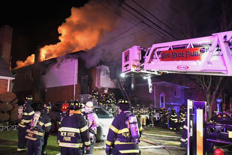 New Hyde Park Fire Department firefighters work the scene of a house fire in New Hyde Park, N.Y., early Sunday Dec. 30, 2018. A young boy who jumped from the window of a burning house was one of three people injured in a fire on Long Island. (Paul Mazza/Newsday via AP)