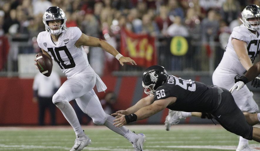 FILE - In this Oct. 20, 2018, file photo, Oregon quarterback Justin Herbert (10) avoids a tackle attempt from Washington State defensive lineman Taylor Comfort (56) during the second half of an NCAA college football game in Pullman, Wash. Herbert has thrown for 6,904 yards with 62 TDs and 17 interceptions in his career, with Oregon averaging 39.4 points per game in his 27 career starts. Oregon plays Michigan State in the Redbox Bowl on Monday. (AP Photo/Young Kwak, File)