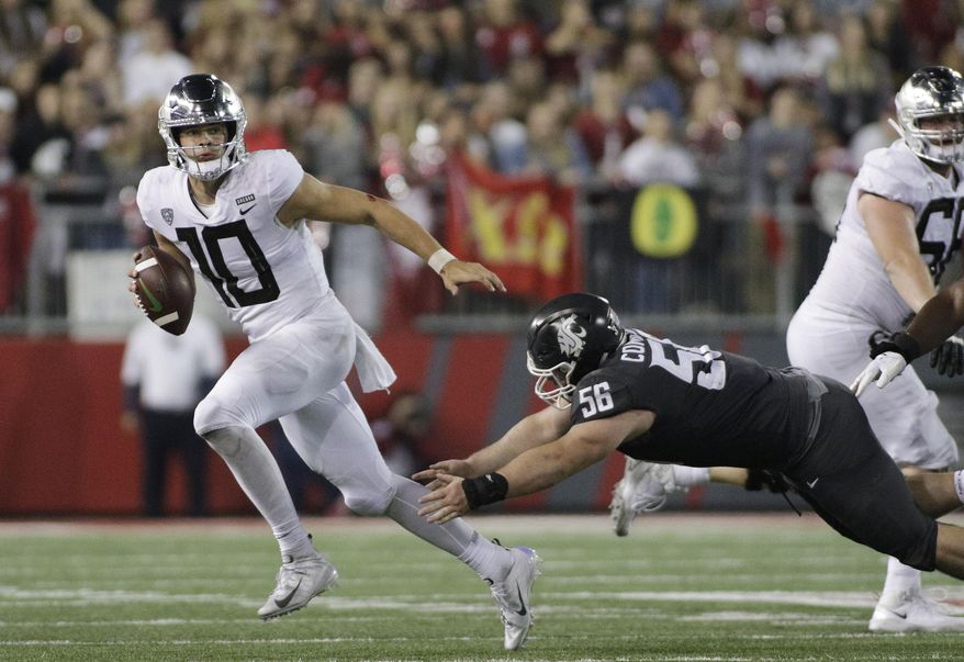 FILE - In this Oct. 20, 2018, file photo, Oregon quarterback Justin Herbert (10) avoids a tackle attempt from Washington State defensive lineman Taylor Comfort (56) during the second half of an NCAA college football game in Pullman, Wash. Herbert has thrown for 6,904 yards with 62 TDs and 17 interceptions in his career, with Oregon averaging 39.4 points per game in his 27 career starts. Oregon plays Michigan State in the Redbox Bowl on Monday. (AP Photo/Young Kwak, File)