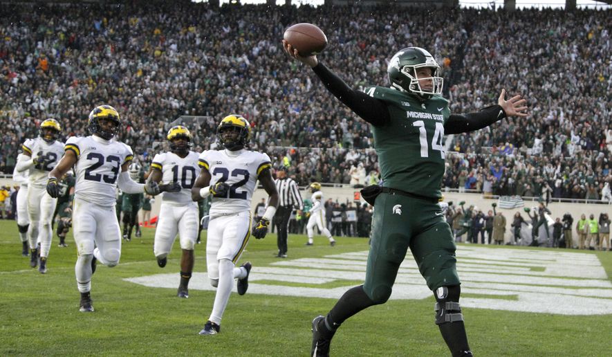 FILE - In this Oct. 20, 2018, file photo, Michigan State quarterback Brian Lewerke, right, celebrates after making a touchdown reception during the third quarter against Michigan in an NCAA college football game in East Lansing, Mich. Michigan State plays Oregon in the Redbox Bowl on Monday. The time off before the bowl did a lot for Lewerke, who missed three games down the stretch with a shoulder injury. Coach Mark Dantonio said Lewerke's arm strength is back and he will start the bowl game. (AP Photo/Al Goldis, File)