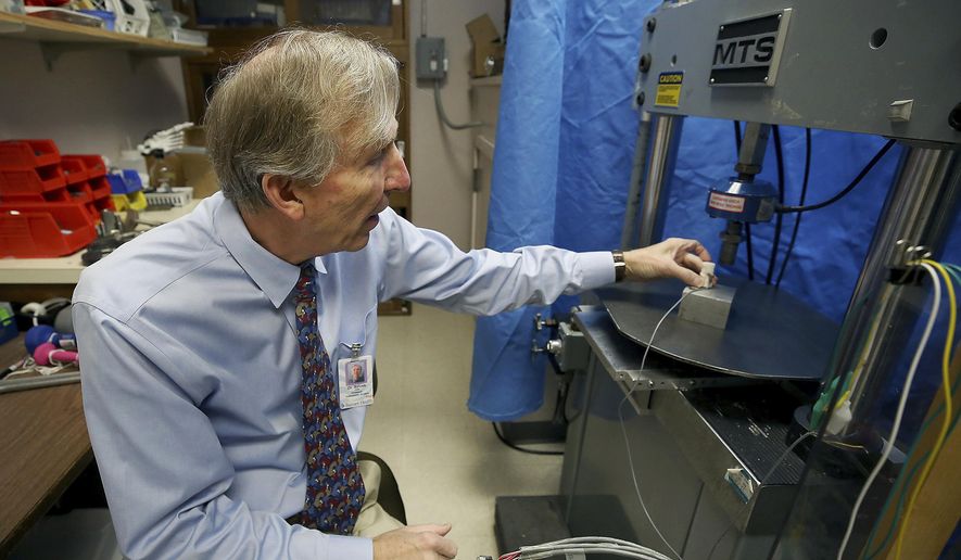 In this Dec. 17, 2018 photo, John Szivek, Rubin chair in orthopedic research professor at the University of Arizona, explains how the scaffold made from a 3-D printer is tested in Tucson, Ariz. Szivek received a $2 million grant from the U.S. Department of Defense to develop technology that could help military personnel recover from bone-shattering injuries using a 3-D printer and adult stem cells. (Mamta Popat /Arizona Daily Star via AP)