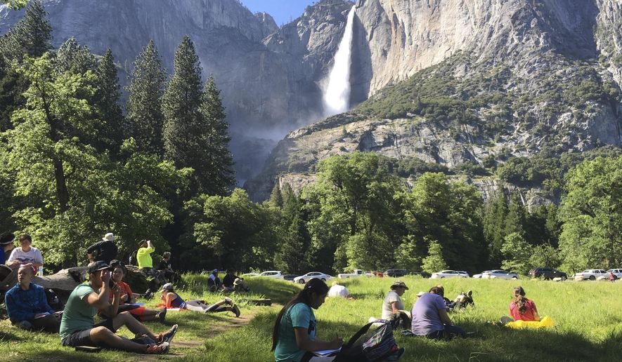 FILE - In this May 25, 2017 file photo, a class of eighth-grade students and their chaperones sit in a meadow at Yosemite National Park, Calif., below Yosemite Falls. Some of the West’s iconic national parks are beginning to partially close as they deal with overflowing restrooms and vandals on the 10th day of a federal government shutdown. (AP Photo/Scott Smith, File)