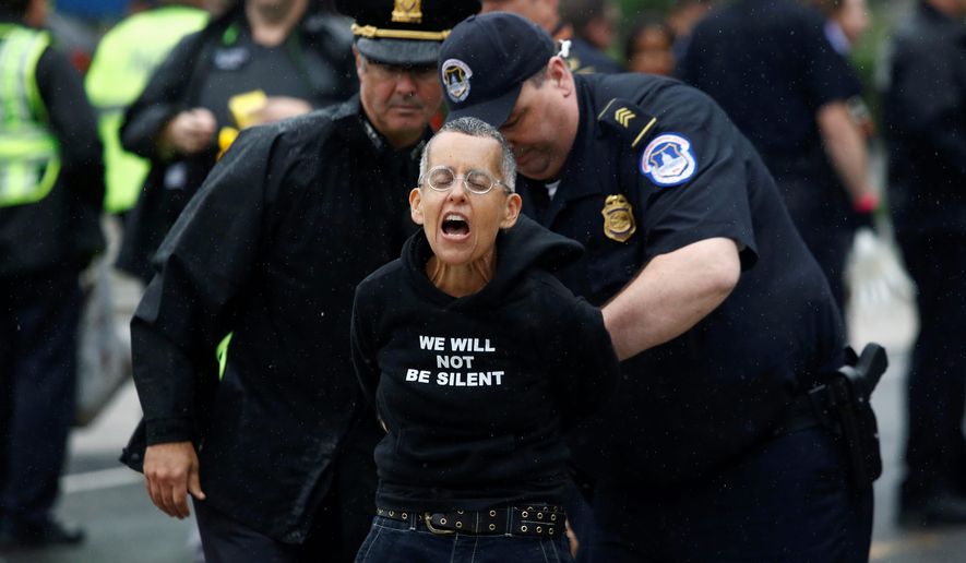 An arrest didn&#39;t stop this protester from yelling while blocking traffic on a street between the Supreme Court and the U.S. Capitol. (Associated Press)