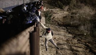 A migrant jumps the border fence to get into the U.S. side to San Diego, Calif., from Tijuana, Mexico, Tuesday, Jan. 1, 2019. Discouraged by the long wait to apply for asylum through official ports of entry, many migrants from recent caravans are choosing to cross the U.S. border wall and hand themselves in to border patrol agents. (AP Photo/Daniel Ochoa de Olza)