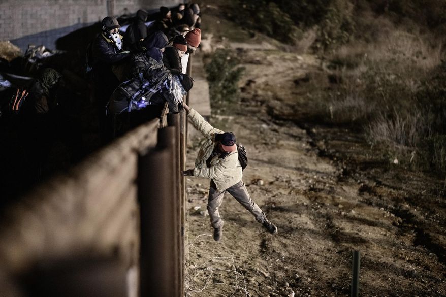A migrant jumps the border fence to get into the U.S. side to San Diego, Calif., from Tijuana, Mexico, Tuesday, Jan. 1, 2019. Discouraged by the long wait to apply for asylum through official ports of entry, many migrants from recent caravans are choosing to cross the U.S. border wall and hand themselves in to border patrol agents. (AP Photo/Daniel Ochoa de Olza)