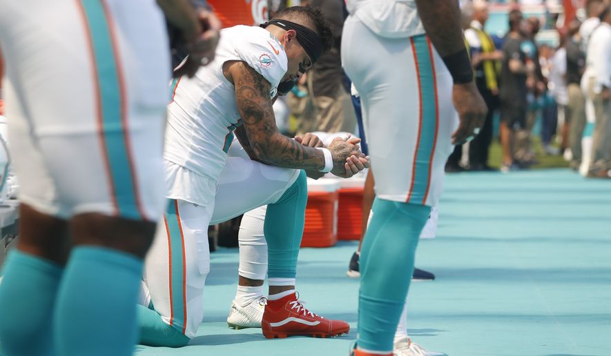 Miami Dolphins wide receiver Kenny Stills and wide receiver Albert Wilson, obscured, take a knee during the singing of the National Anthem before the start of an NFL football game against the Oakland Raiders, Sunday, Sept. 23, 2018 in Miami Gardens, Fla. (AP Photo/Brynn Anderson)