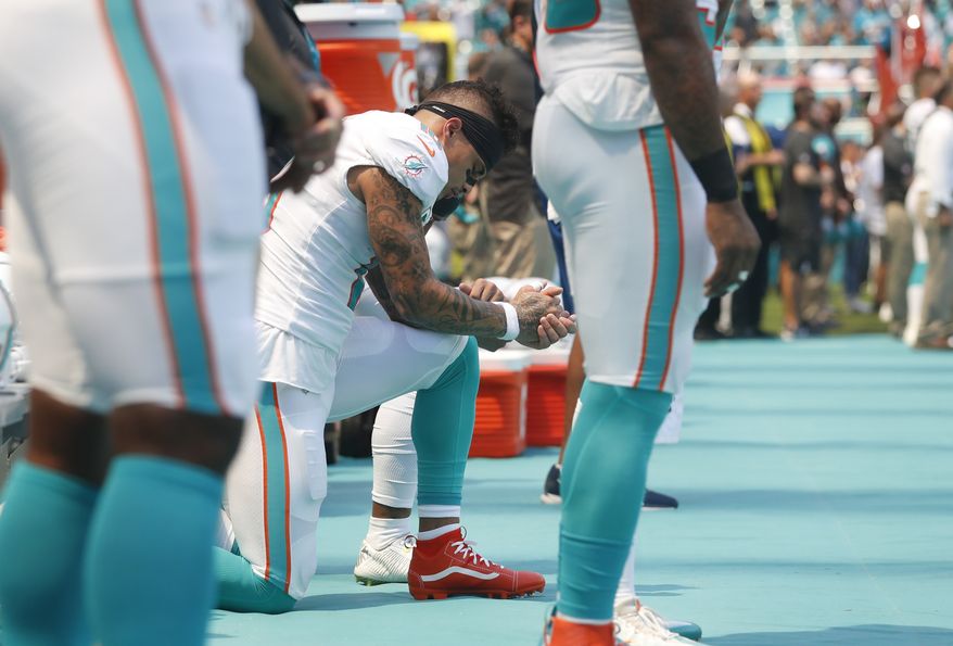 Miami Dolphins wide receiver Kenny Stills and wide receiver Albert Wilson, obscured, take a knee during the singing of the National Anthem before the start of an NFL football game against the Oakland Raiders, Sunday, Sept. 23, 2018 in Miami Gardens, Fla. (AP Photo/Brynn Anderson)