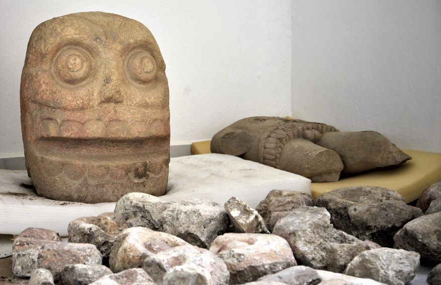 In this 2018 photo provided by Mexico's National Institute of Anthropology and History, INAH, a skull-like stone carving and a stone trunk depicting the Flayed Lord, a pre-Hispanic fertility god depicted as a skinned human corpse, are stored after being excavated from the Ndachjian–Tehuacan archaeological site in Tehuacan, Puebla state, where archaeologists have discovered the first temple dedicated to the deity. Although depictions of the god, Xipe Totec, had been found before in other cultures, a whole temple had never been discovered. (Meliton Tapia Davila/INAH via AP)