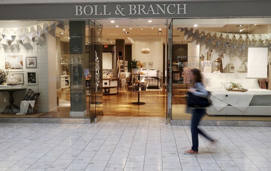 FILE - In this Nov. 2, 2018 file photo, a patron at the Mall at Short Hills in Short Hills, N.J., passes the Boll & Branch furniture store. Shoppers looking for high quality sheets without hurting their budget may want to skip the so-called White Sales at mass retailers. Startups, including Parachute, Brooklinen, and Boll & Branch are cutting out middlemen and selling directly to customers online at a fraction of the price it would normally cost at high-end stores. (AP Photo/Ted Shaffrey)