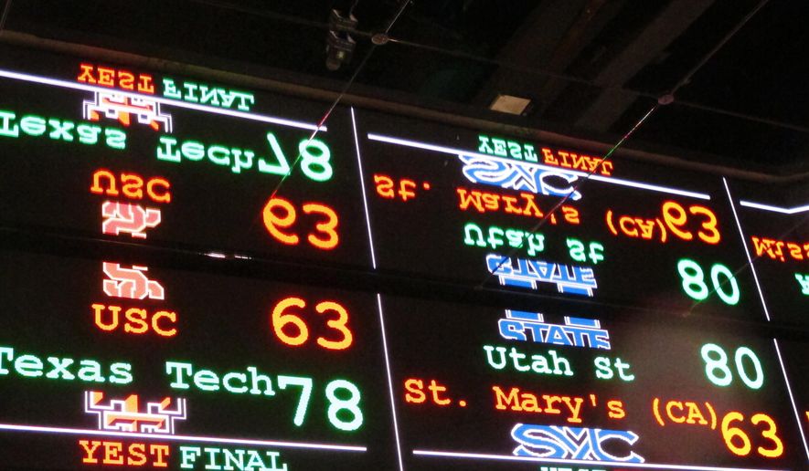 FILE This Nov. 20, 2018 file photo shows a scrolling video board with basketball scores reflected in the ceiling of the new sports book at Resorts Casino in Atlantic City, N.J. The race to legalize sports betting is on now that the U.S. Supreme Court has allowed it in all 50 states, but will it provide enough extra tax revenue to make much of a difference for schools, roads or pension debt? (AP Photo/Wayne Parry)