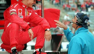 FILE - In this July 25, 1997, file photo, Germany&#39;s Michael Schumacher, left, of the Ferrari team, shares a joke with Benetton chief Flavio Briatore, right, at the start of the first free practice session for the upcoming German Formula 1 Grand Prix in Hockenheim. Against the backdrop of celebrations marking Michael Schumacher’s 50th birthday Thursday, Jan. 3, 2019, the medical condition of Formula One&#39;s most successful driver remains just as fiercely guarded by his close family. (AP Photo/Thomas Kienzle, File)