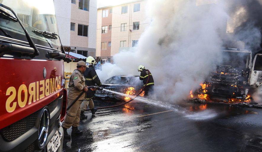 Firefighters put out torched vehicles on a street after attacks in the city of Fortaleza, northeastern Brazil, Thursday, Jan. 3, 2019. Brazil's newly inaugurated government has ordered military police sent to Ceara state following a wave of attacks on banks, public buildings and infrastructure over the past two days, which have hit 15 cities, including the capital. (AP Photo/Alex Gomes/O Povo)