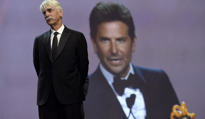 Sam Elliott looks on as Bradley Cooper, seen in background screen, accepts the director of the year award for "A Star Is Born" at the 30th annual Palm Springs International Film Festival on Thursday, Jan. 3, 2019, in Palm Springs, Calif. Looking on at right is (Photo by Chris Pizzello/Invision/AP)