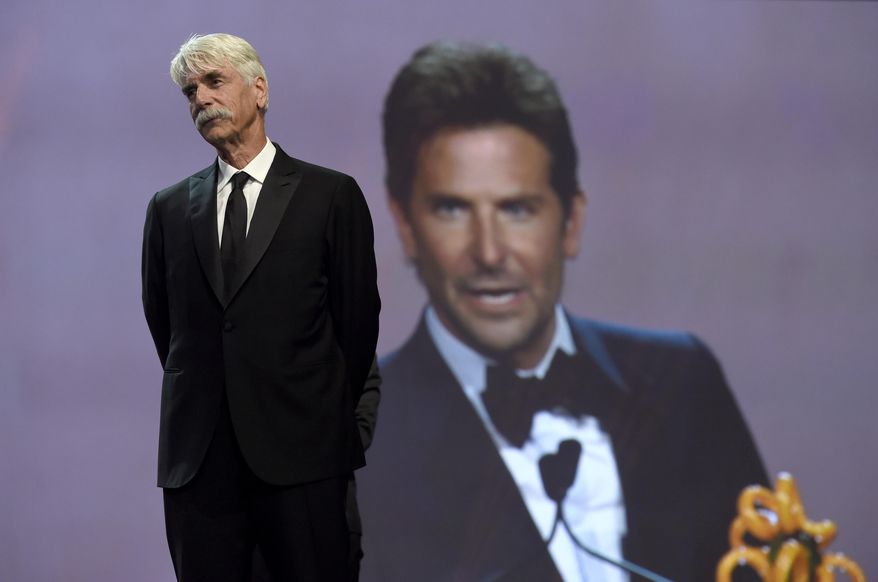 Sam Elliott looks on as Bradley Cooper, seen in background screen, accepts the director of the year award for "A Star Is Born" at the 30th annual Palm Springs International Film Festival on Thursday, Jan. 3, 2019, in Palm Springs, Calif. Looking on at right is (Photo by Chris Pizzello/Invision/AP)