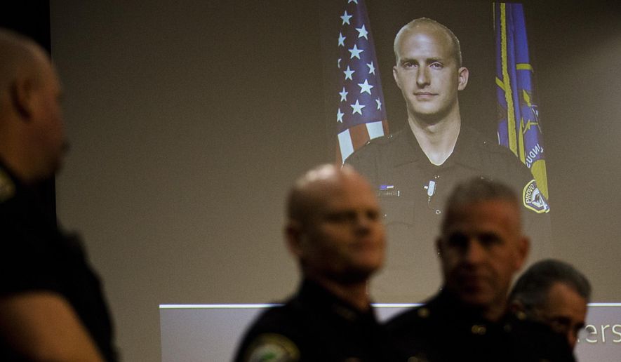 A picture of Joseph Shinners, a Provo police officer who was killed in the line of duty, is projected at the Provo City Center building during a news conference on Sunday, Jan. 6, 2019, in Provo, Utah. Shinners, who was shot and killed while trying to apprehend a fugitive, was a three-year veteran of the force who managed to shoot back and strike the suspect at least once after he was hit by gunfire. (Evan Cobb/The Daily Herald via AP)
