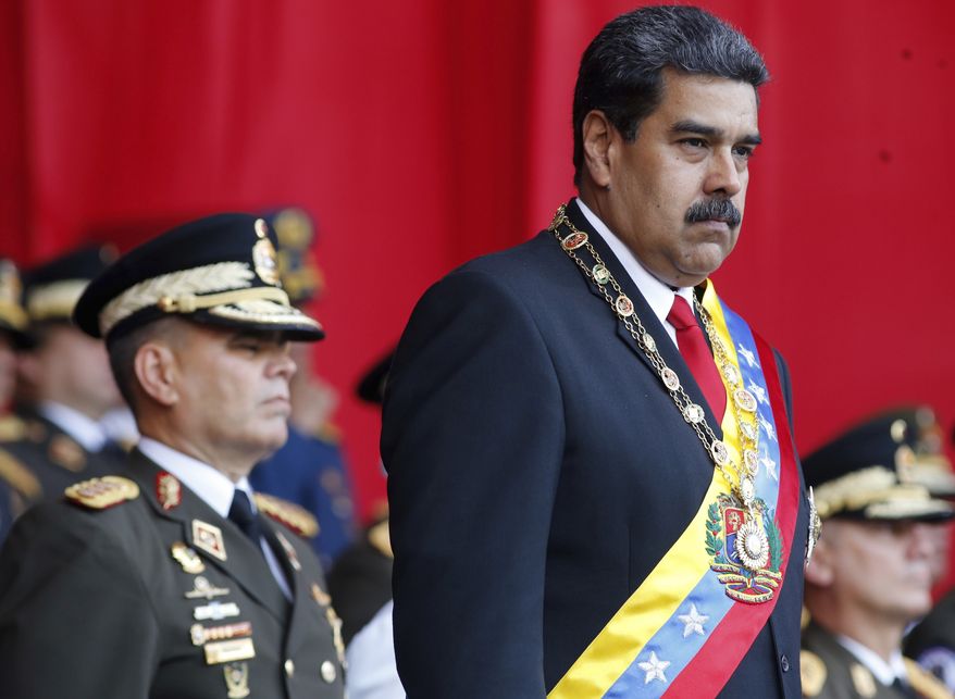 FILE - In this  May 24, 2018 file photo, Venezuela&#x27;s President Nicolas Maduro watches a military parade, alongside his Defense Minister Vladimir Padrino Lopez, behind, at Fort Tiuna in Caracas, Venezuela. State television in Venezuela showed President Maduro abruptly cutting short a speech on Saturday, Aug. 4, causing hundreds of soldiers present to break ranks and scatter.(AP Photo/Ariana Cubillos, File)