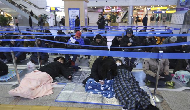 People sleep as they wait to buy train tickets for their hometown visits during Lunar New Year holidays at Seoul Railway Station in Seoul, South Korea, Tuesday, Jan. 8, 2019. South Koreans will visit their hometowns during a five-day holiday of the Lunar New Year which falls on Feb. 5 this year. (AP Photo/Ahn Young-joon) ** FILE **