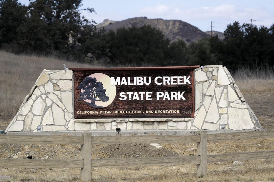 FILE - In this Oct. 11, 2018 file photo a sign is seen at the entrance to the Malibu Creek State Park in Calabasas, Calif. The arraignment of a parolee charged with killing a man camping with his daughters at a Southern California state park in June and shooting at 10 people over the past two years has been postponed. Prosecutors said Monday, Jan. 7, 2019, that arraignment for Anthony Rauda was continued until Jan. 22 in Los Angeles County Superior Court. (AP Photo/Marcio Jose Sanchez,File)