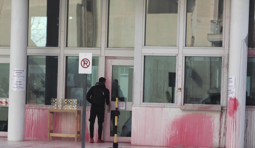 A man stands at an entrance of the US embassy in Greece, some hours after an anarchist group threw red paint, in Athens, on Monday, Jan. 7, 2019. Police said Monday that eight were detained after about 10 people on motorbikes threw red paint at the embassy's parking entrance at around 3:30 a.m. local time. An anarchist group known as Rouvikonas claimed responsibility for the attack in an internet post. (AP Photo/Petros Giannakouris)