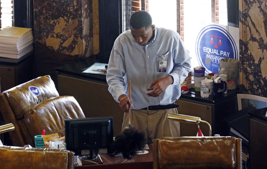 Devon Davis, a porter with the Mississippi State Senate, dusts one of senators' desks on the chamber floor, a final time on Monday, Jan. 7, 2019, at the Capitol in Jackson, Miss., as the legislative staffs work at readying the building for Tuesday's start of the 2019 Mississippi Legislature. (AP Photo/Rogelio V. Solis)