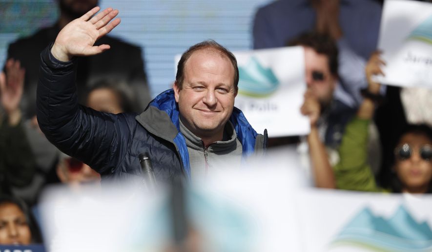 FILE - In this Wednesday, Oct. 24, 2018, file photograph, Jared Polis, Colorado's governor-elect, waves to voters before U.S. Senator Bernie Sanders speaks during a rally with young voters on the campus of the University of Colorado in Boulder, Colo. Polis will take the oath of office Tuesday, Jan. 8, 2019, to become the nation's first, openly-gay governor. (AP Photo/David Zalubowski, File)